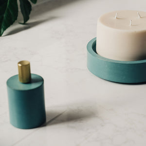 concrete and wax lifestyle shot with candle snuffer and teal concrete candle plate